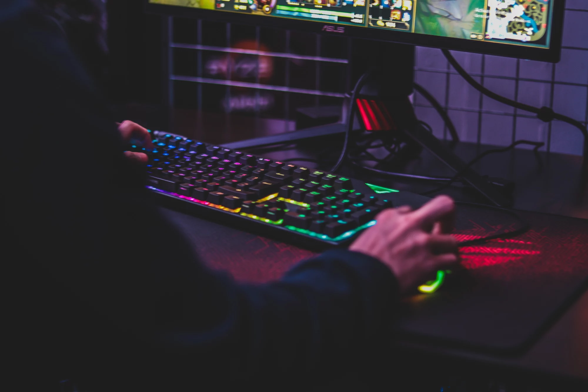person gaming on PC with RGB light up keyboard and mouse
