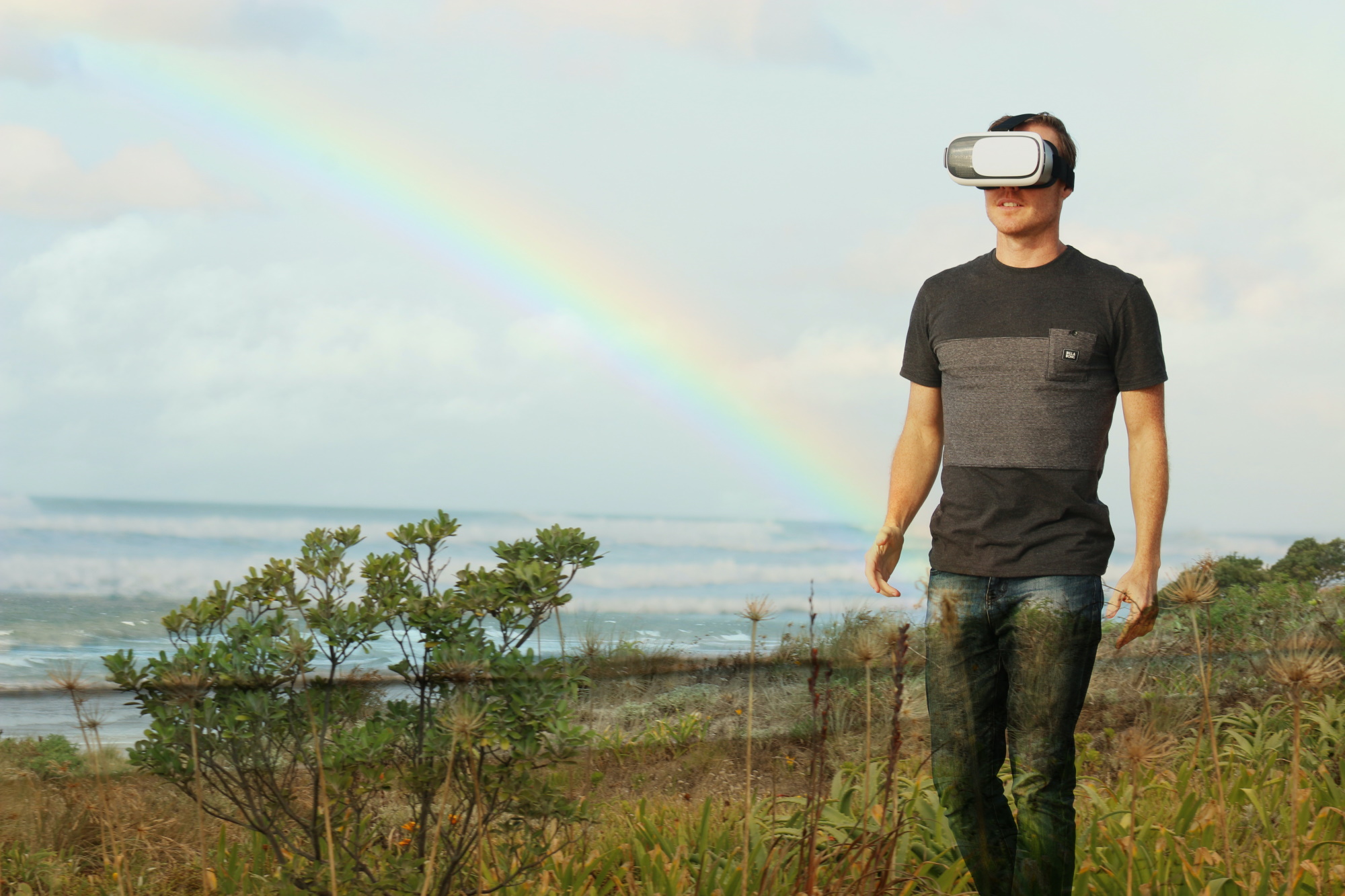 male wondering outside wearing VR headset with rainbow in background