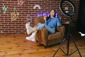 female sitting on chair recording video with ring light